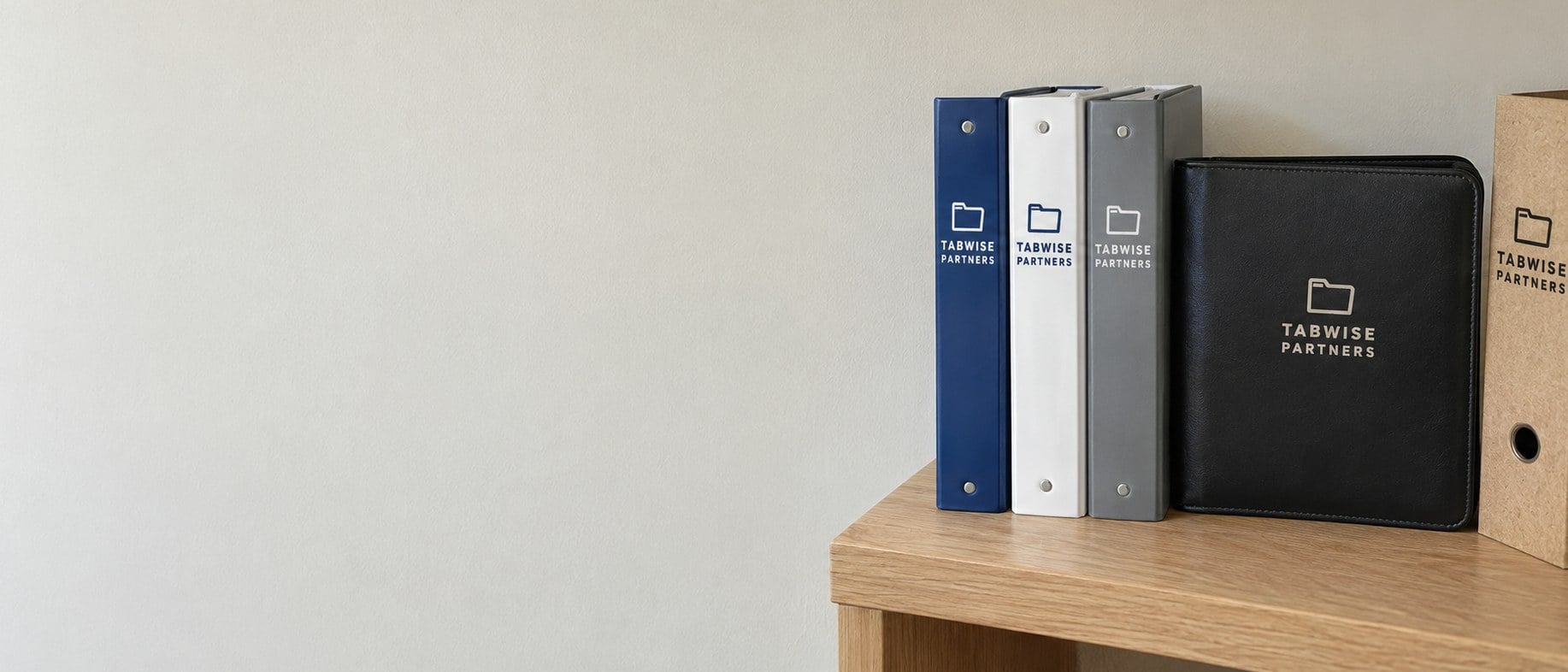 Custom printed ring binders standing upright on a light oak office shelf